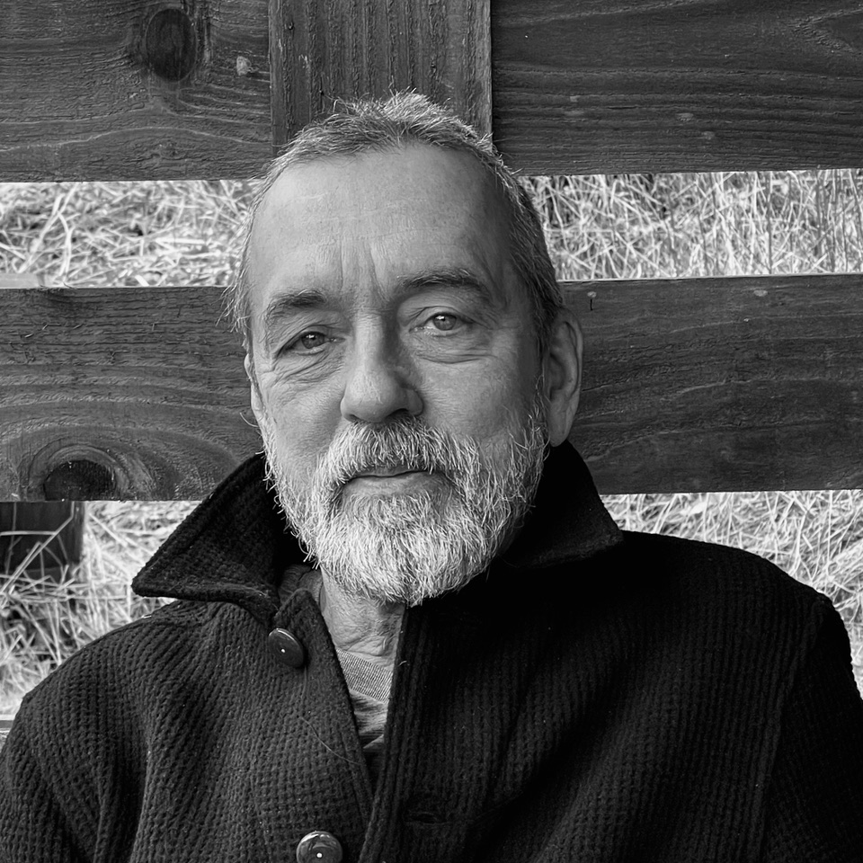 David Noble in front of a wooden gate in black and white