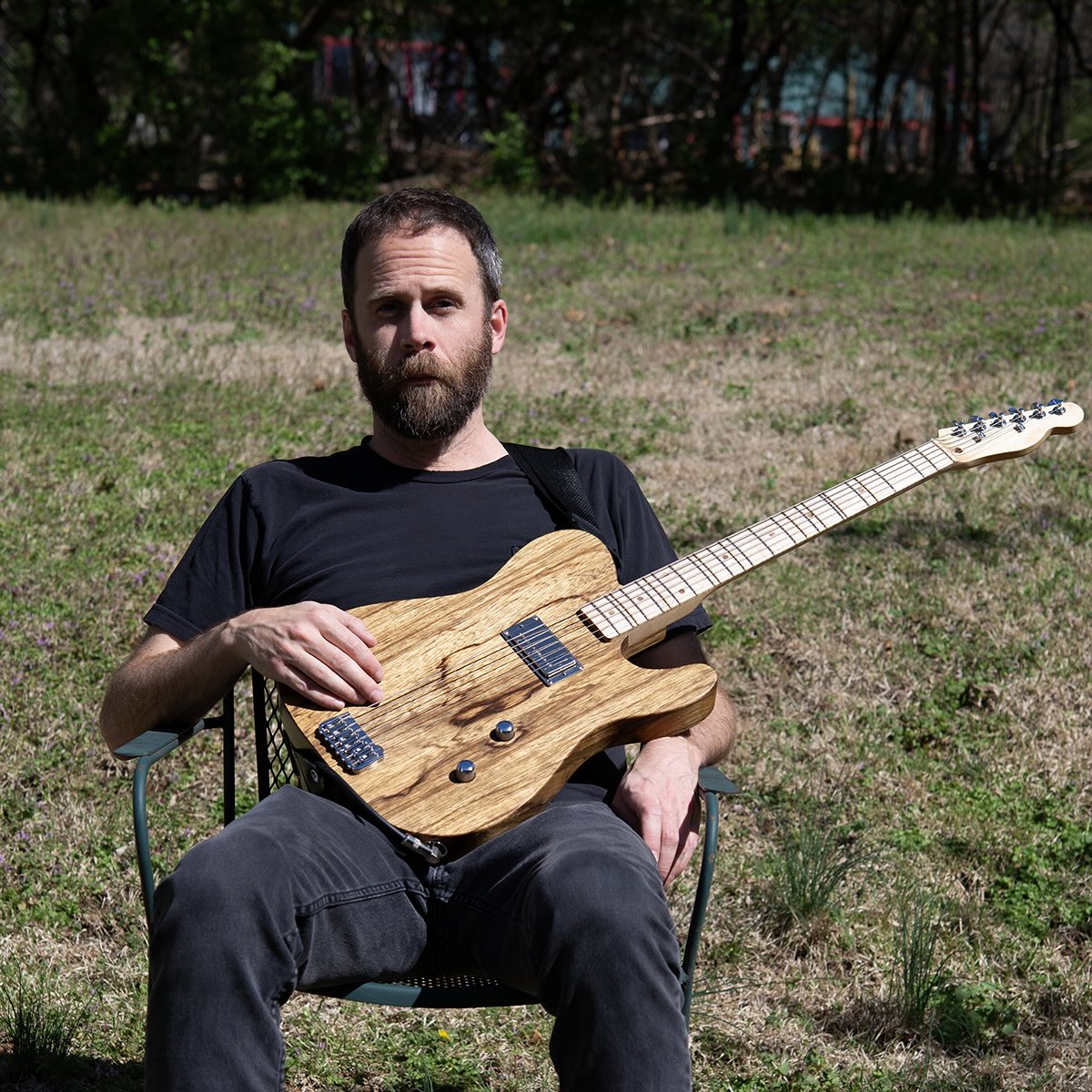 Sam sitting in a chair with a guitar.